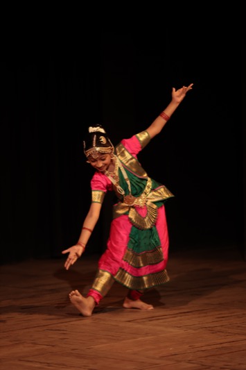 Child performing a classical dance solo on stage
