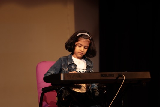 Child playing a keyboard on stage at WKC Showcases